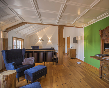 Großes Hotelzimmer mit Holzboden, blauen Möbeln und grüner Wand
